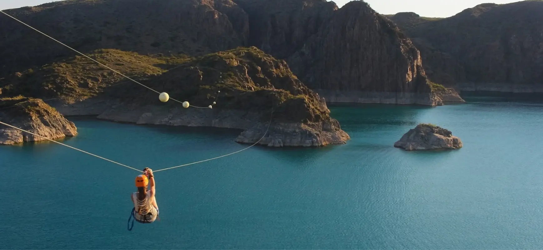 Una persona tirándose en tirolesa a través de un gran lago